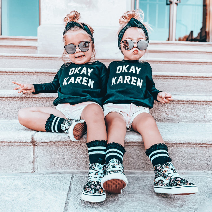 Two children sitting on steps wearing matching outfits with 'OKAY KAREN' text.