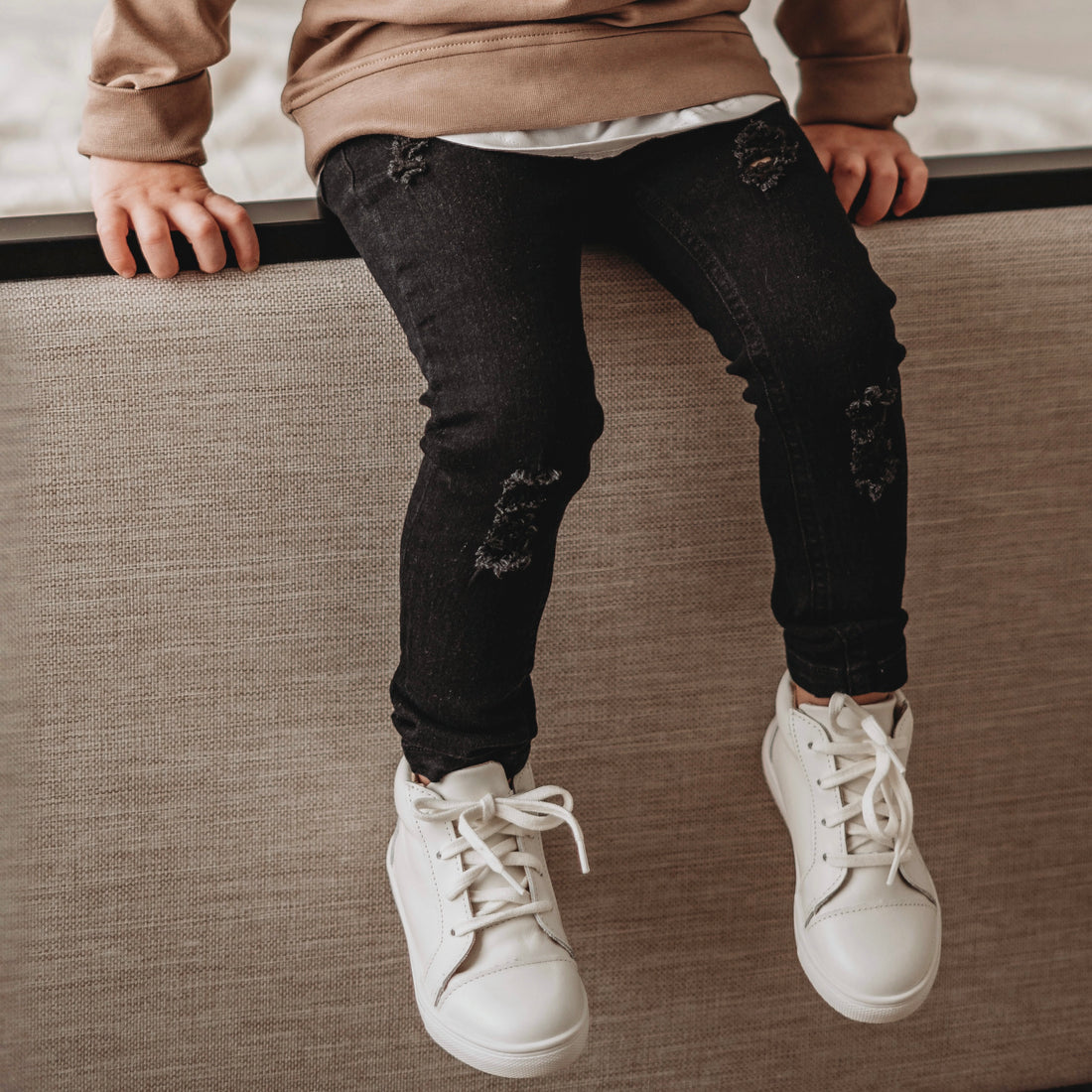 Child wearing LENOX JAMES black distressed stretch jeans with white sneakers